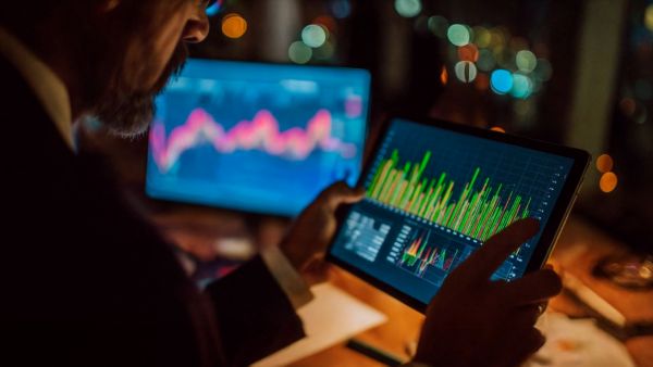 Homem segurando tablet com gráfico de ações para comprar call ou put