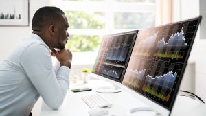 Investidor analisando desempenho de diferentes ativos na bolsa de valores antes de aplicar seu dinheiro