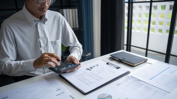 Investidor usando calculadora para usar métrica financeira WACC para definir onde investir seu dinheiro