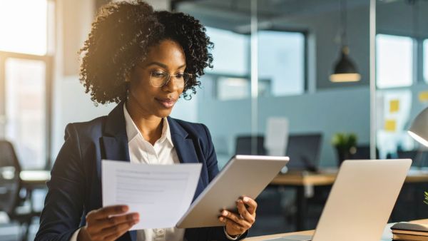 Investidora comparando dados de empresas com preços dos ativos na B3 antes de investir