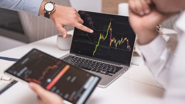 Investidores analisando preços de ativos além de dados das empresas para fazer aplicações rentáveis e seguras