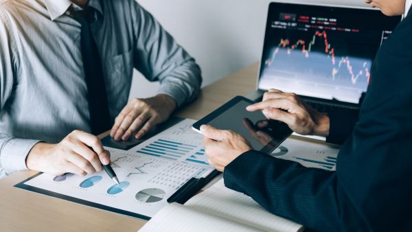 Investidores definindo estratégia de investimento em conjunto enquanto analisam empresas