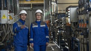 Colaboradores de empresa ao lado de máquinas e equipamentos-que compõem os bens de capital de empresa