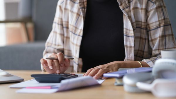 Investidora calculando custos de operação de investimento antes de efetivamente abrir posição