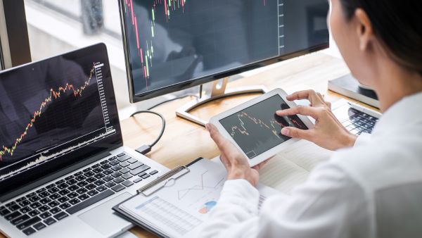 Investidora usando múltiplas telas para acompanhar mudança de cotações de ativos na B3, antiga Bovespa