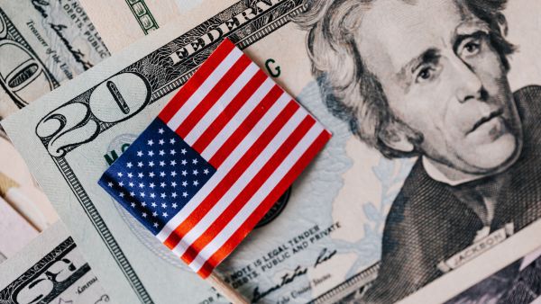 Notas de dólar junto com pequena bandeira dos Estados unidos representando investimento na bolsa de valores Nasdaq