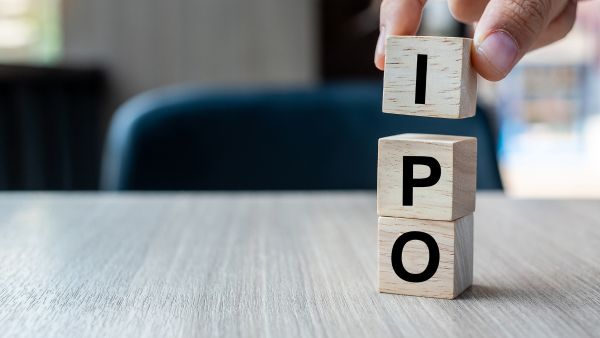 Pessoa empilhando blocos de madeira com letras que formam as iniciais IPO