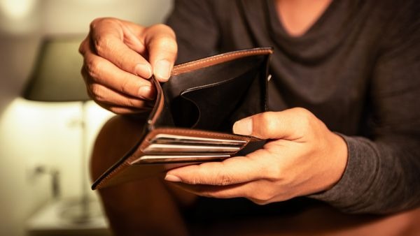 Pessoa abrindo carteira vazia representando a falta de liquidez de investimentos