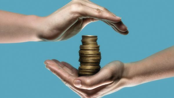 Duas mãos em volta de pilha de moedas representando o conceito de custódia de investimentos