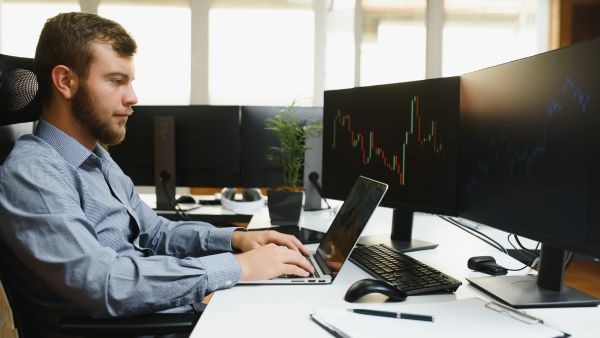 Investidor usando múltiplas telas-para agir rápido e lucrar com arbitragem