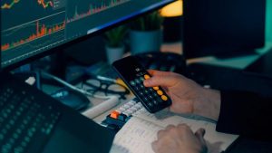 Investidor calculando valores de operação de CFDs antes de abrir posição para lucrar com variação de preço