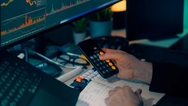 Investidor calculando valores de operação de CFDs antes de abrir posição para lucrar com variação de preço