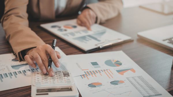 Investidor fazendo cálculos e analisando dados de empresa para saber se aplicação compensa