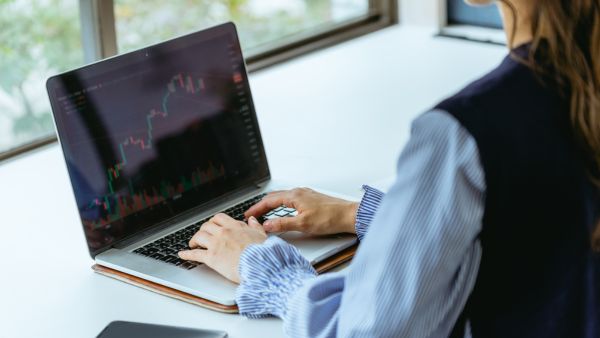 Investidora vendo gráfico de variação de preço de ativos após analisar demonstrações e guidance da empresa para investir