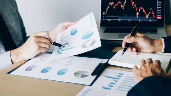 Investidores analisando dados de empresas para investir estrategicamente no mercado de capitais