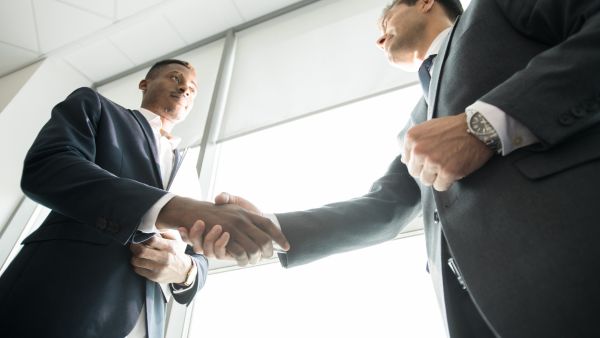 Investidor e gestor se cumprimentando em evento após conversa sobre skin in the game