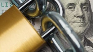 Nota de dólar com cadeado e corrente por cima representando o conceito de lock-up